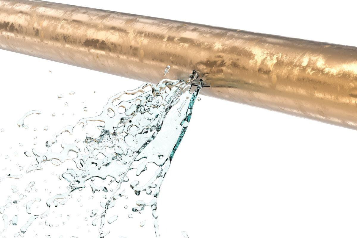 A copper pipe with a leak, spraying water.