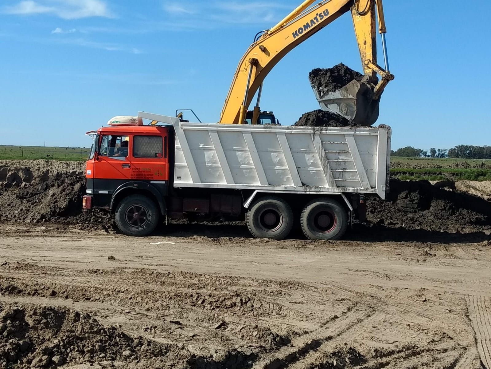 Obreros de la construcción con cascos y chalecos de seguridad revisando planos en una obra.