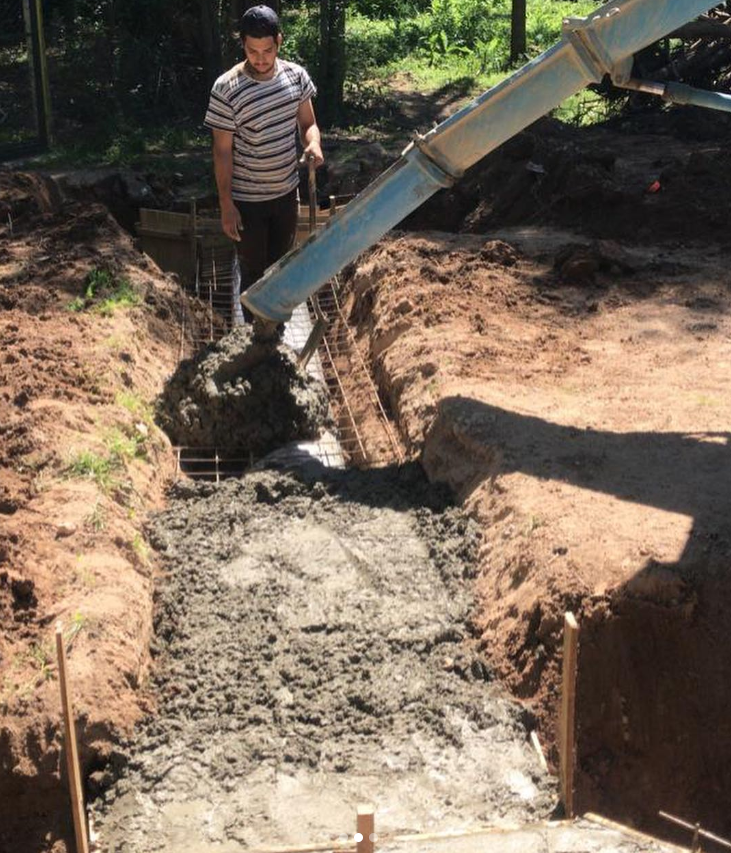 Un trabajador vierte hormigón en una zanja en una obra de construcción.