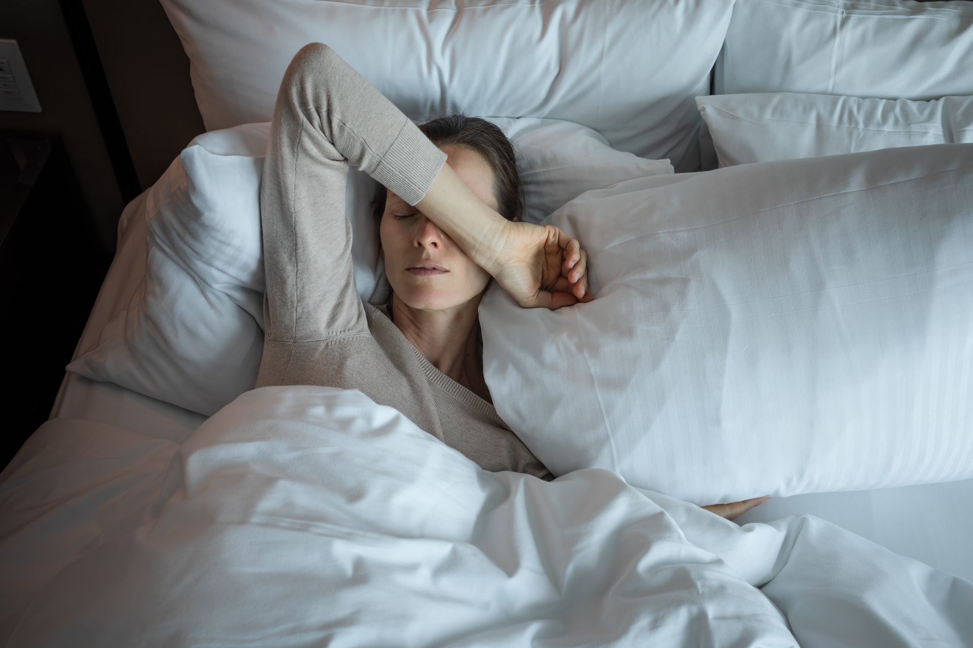 People in white t-shirts are fixated on their smartphones, lit by a dim light.