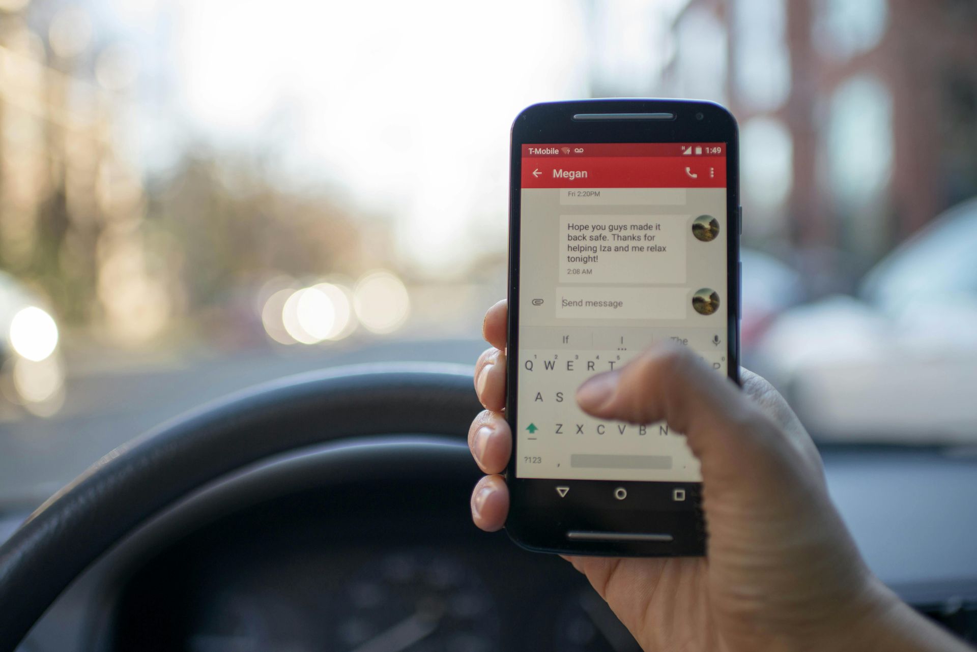 Person texting on a phone while holding a steering wheel, possibly driving.
