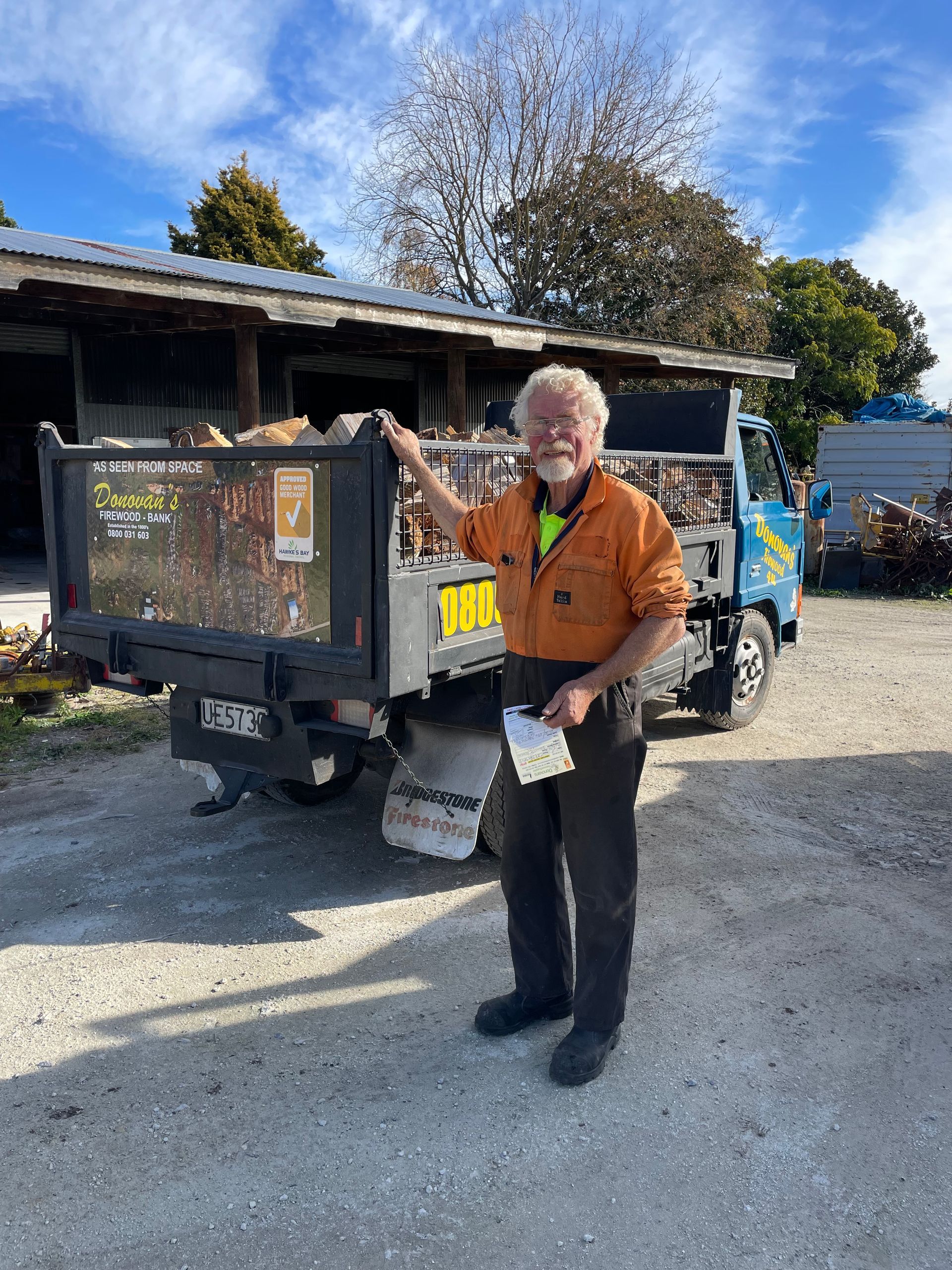 A man is standing in front of a dump truck holding a piece of paper.