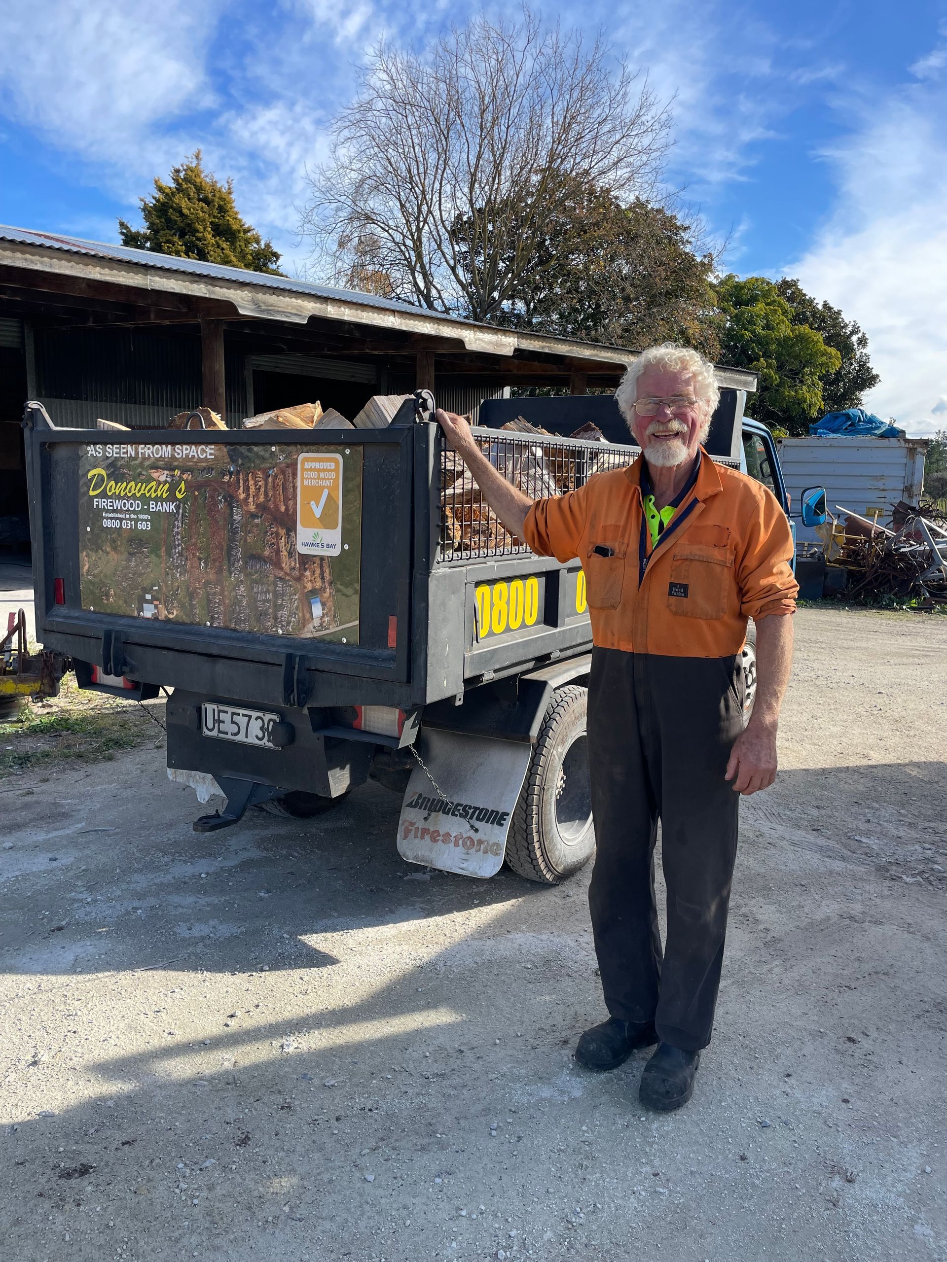 A man is standing in front of a dump truck.