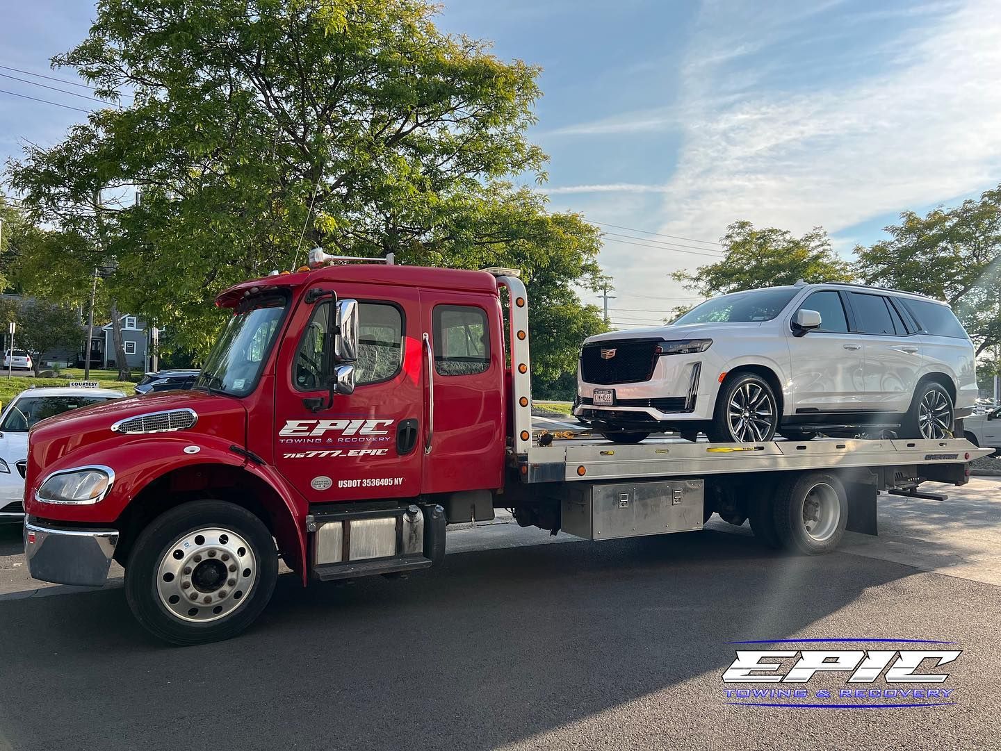 Red tow truck carrying a damaged white SUV on a flatbed trailer