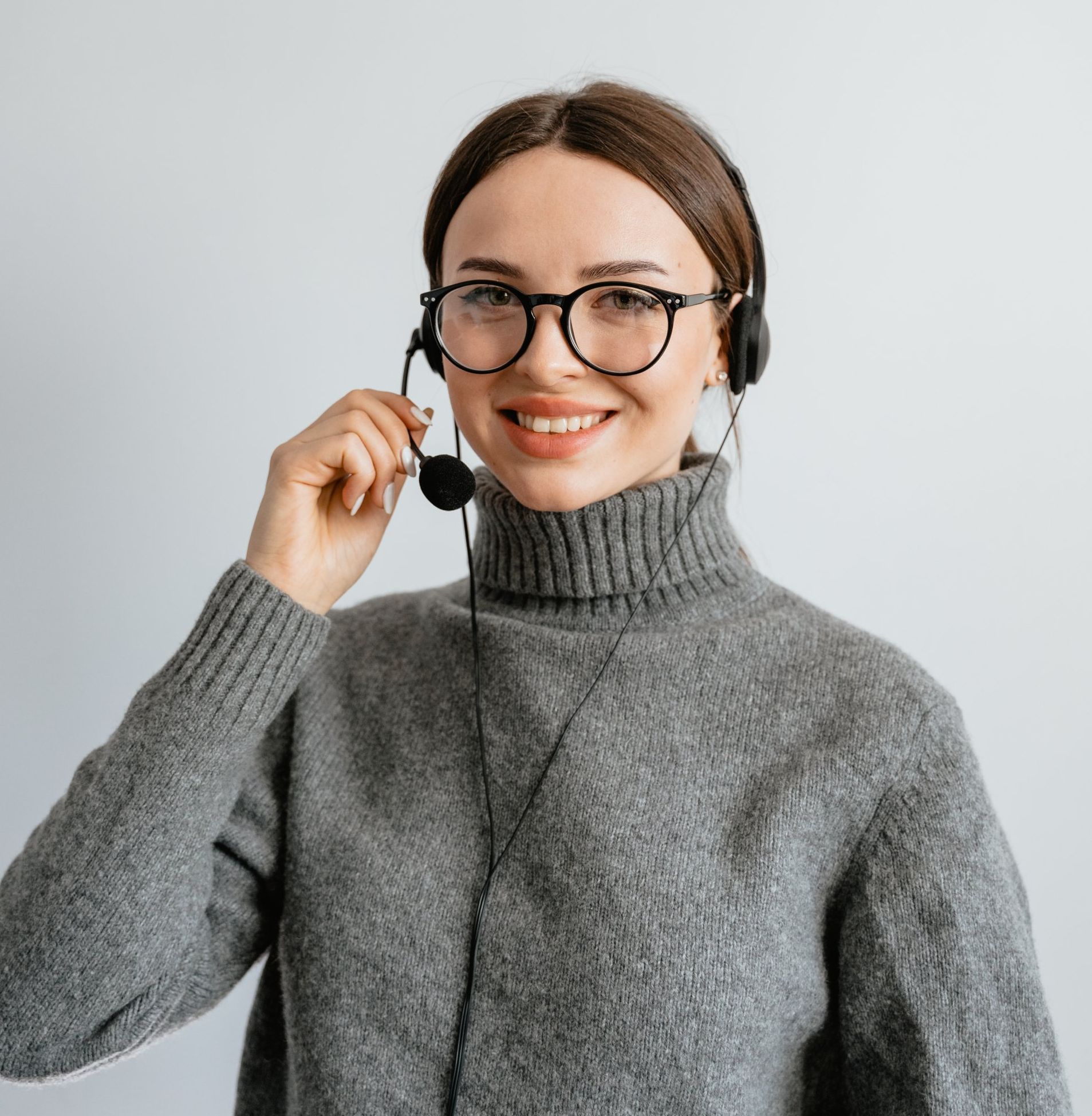 Femme avec des lunettes et un casque souriant, portant un col roulé gris.