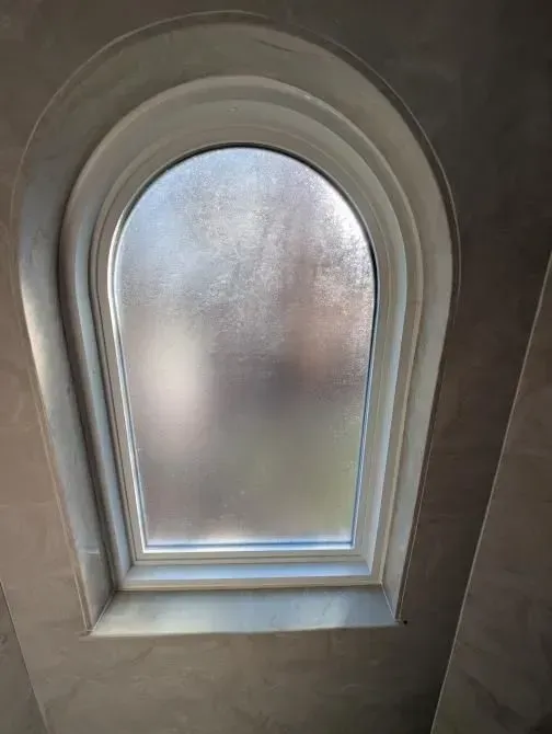A round window with a frosted glass window in a room.