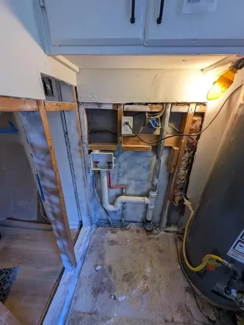 A bathroom with a water heater and pipes coming out of the wall.