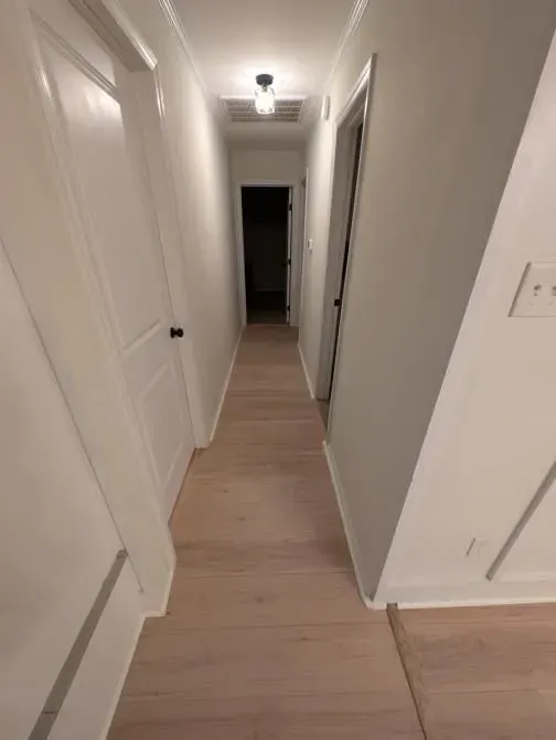 A long hallway with hardwood floors and white walls.