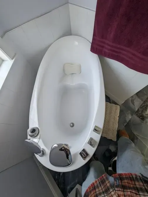A white bathtub in a bathroom next to a purple towel