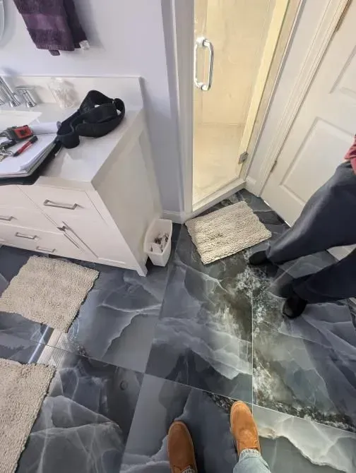 A person standing on a tiled floor in a bathroom