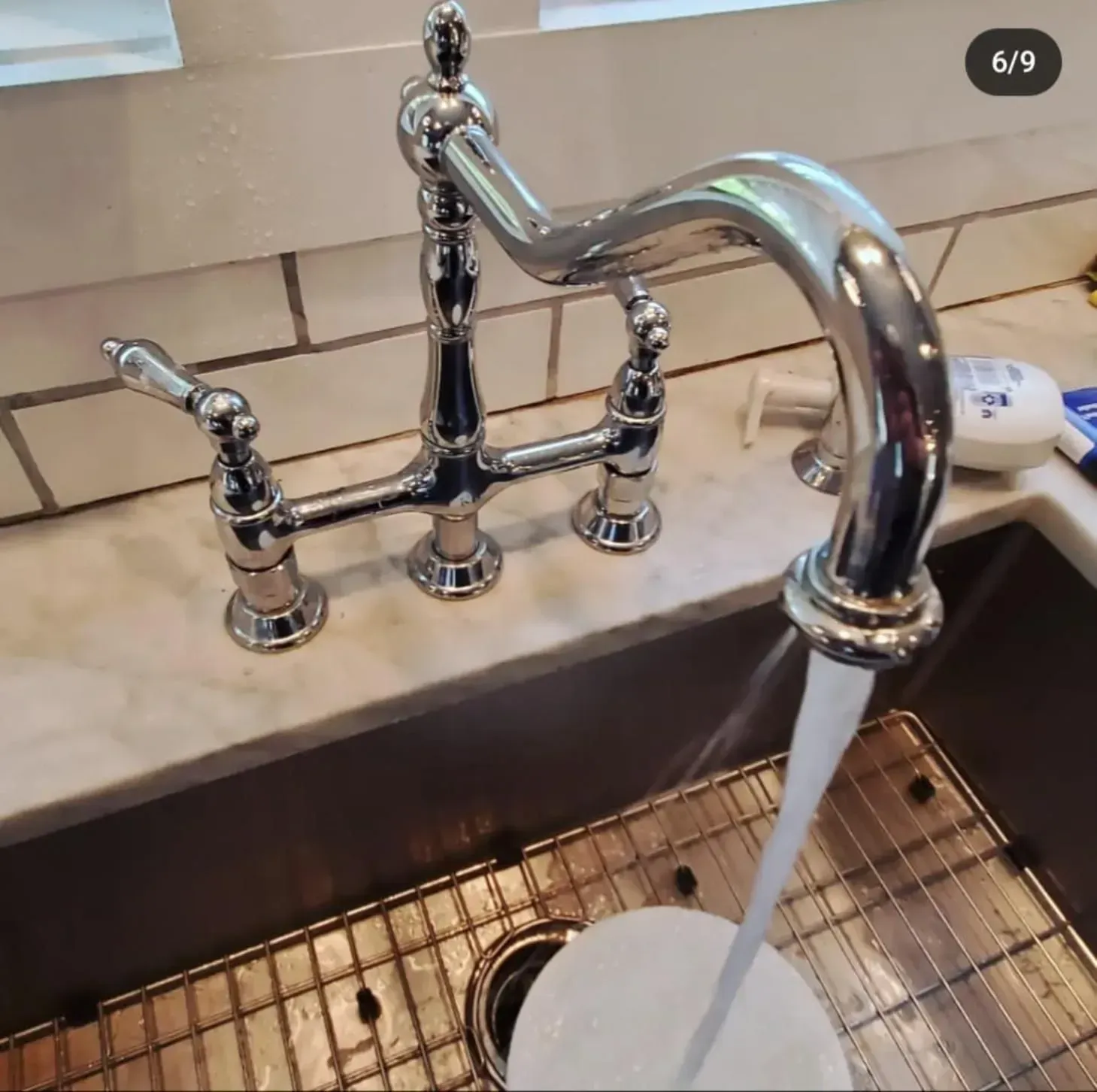 A close up of a kitchen sink with water running from the faucet