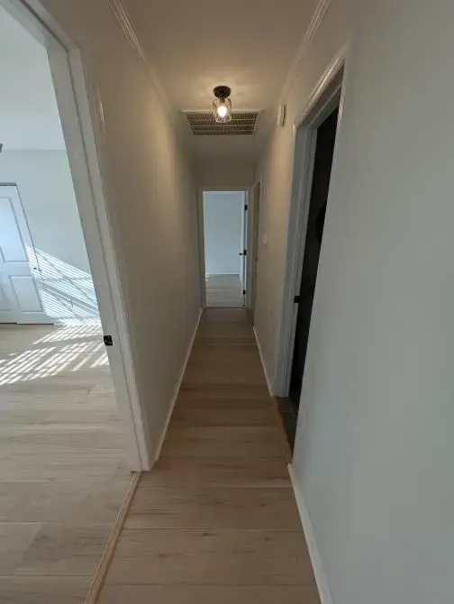 A long hallway in a house with hardwood floors and white walls.