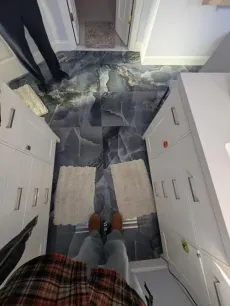 A person standing in a bathroom with a marble floor