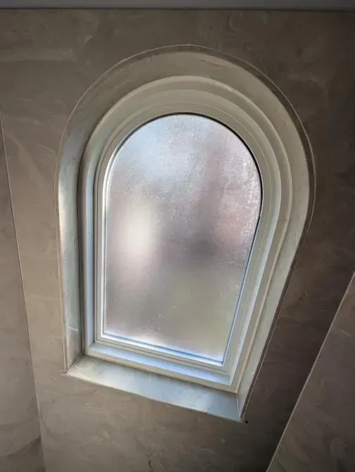 A round window with a frosted glass window in a room.