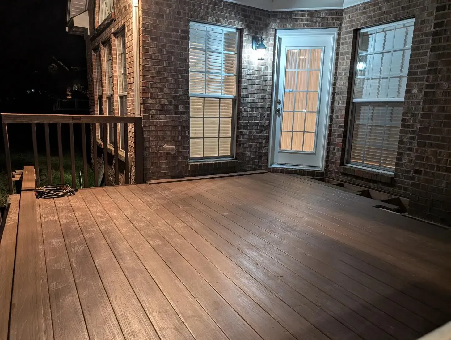 A wooden deck in front of a brick building at night.