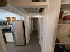 A long hallway leading to a kitchen with a refrigerator
