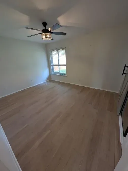An empty room with a ceiling fan and a window.