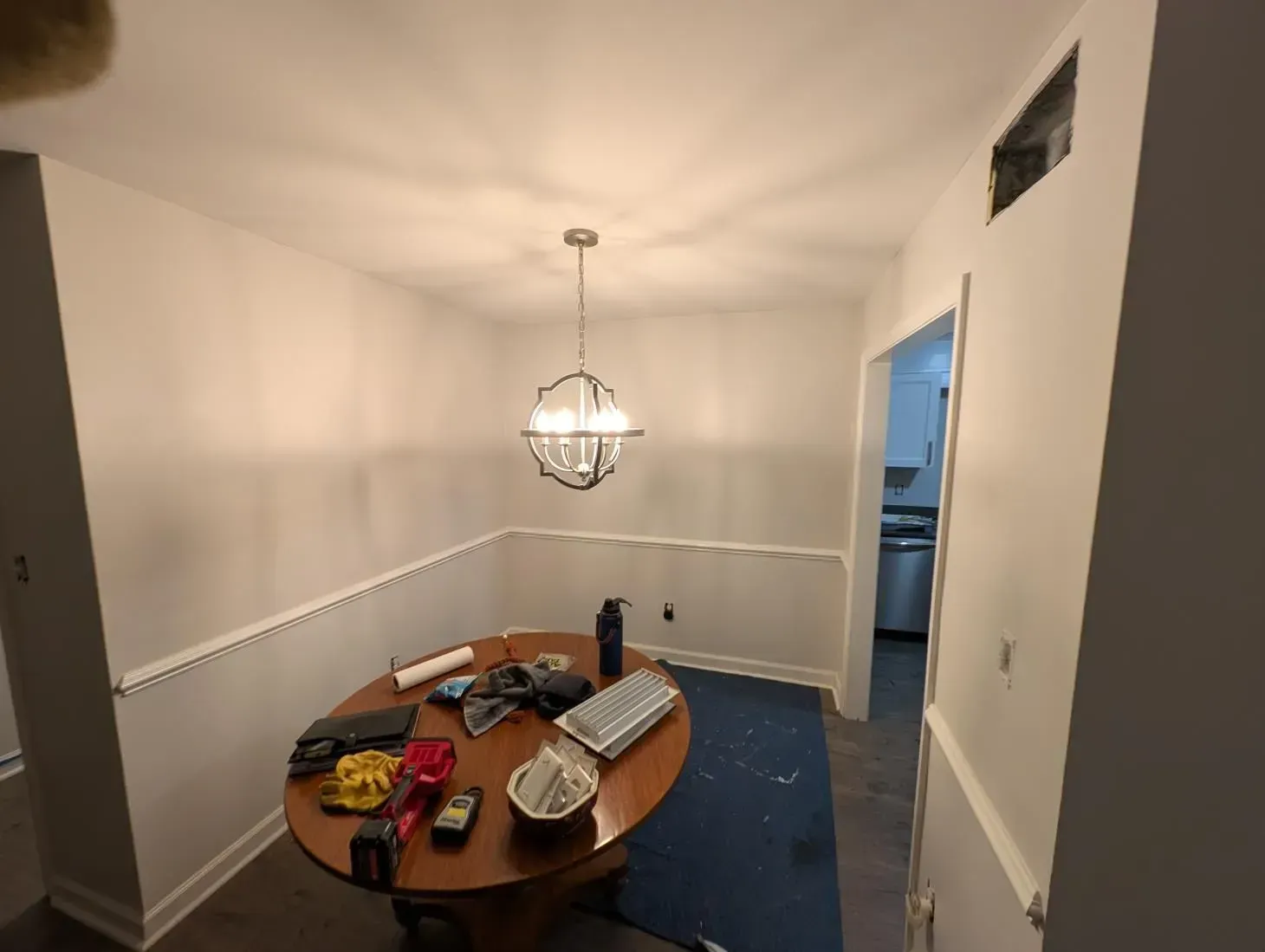 A dining room with a round table and a chandelier hanging from the ceiling.