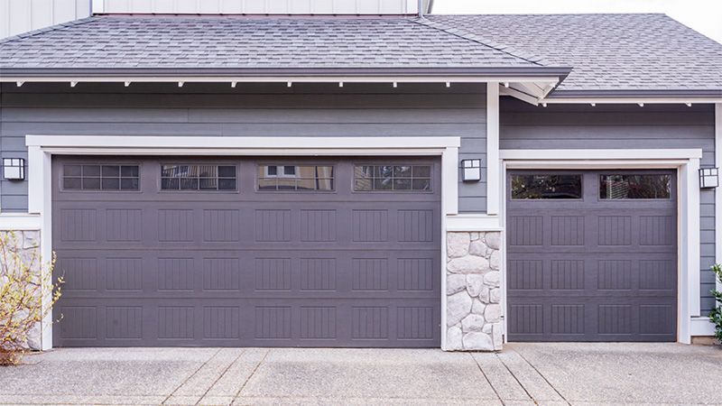 There are two garage doors on the side of a house.
