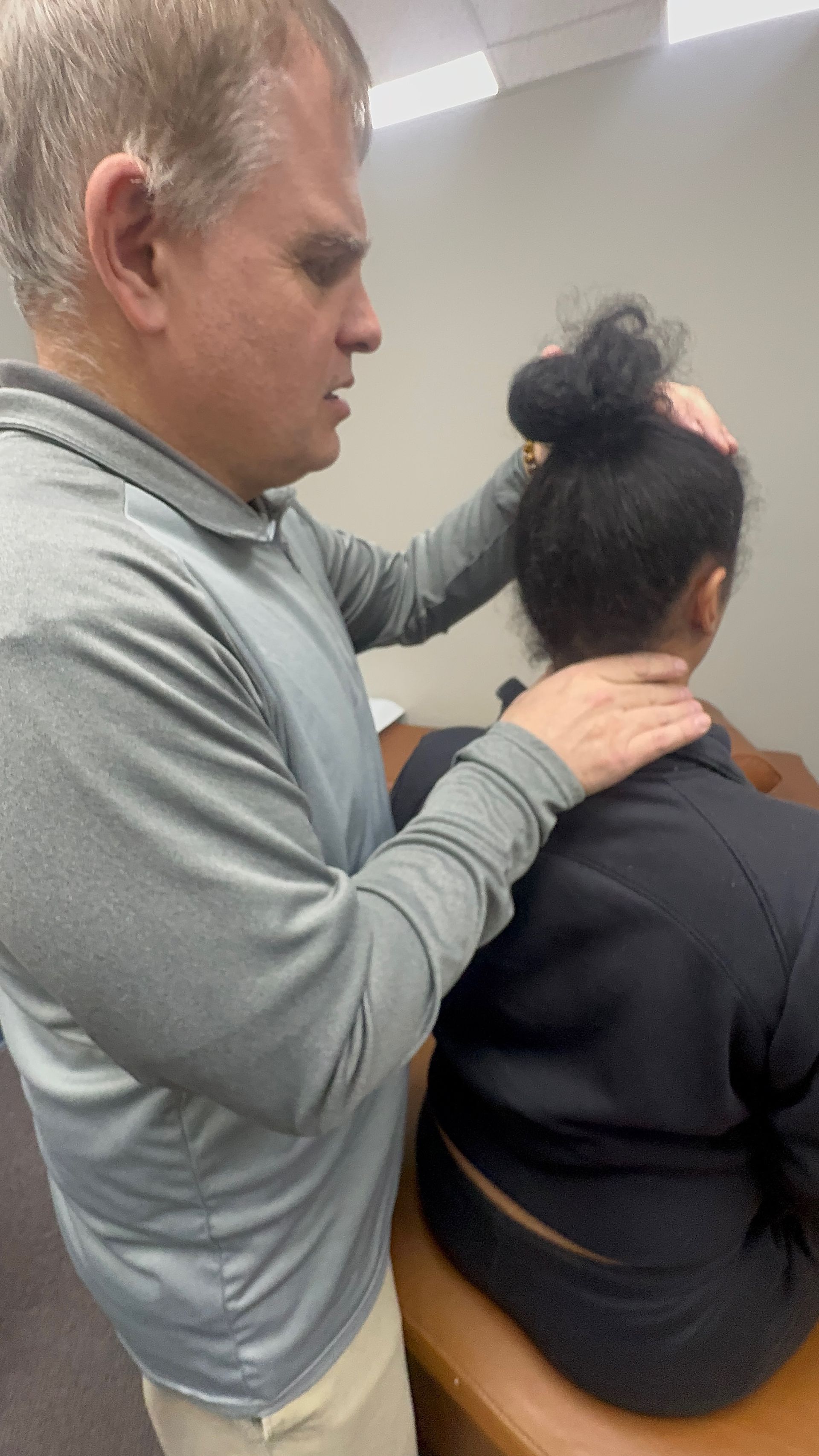 A person is receiving neck manipulation from a healthcare provider in an office setting.