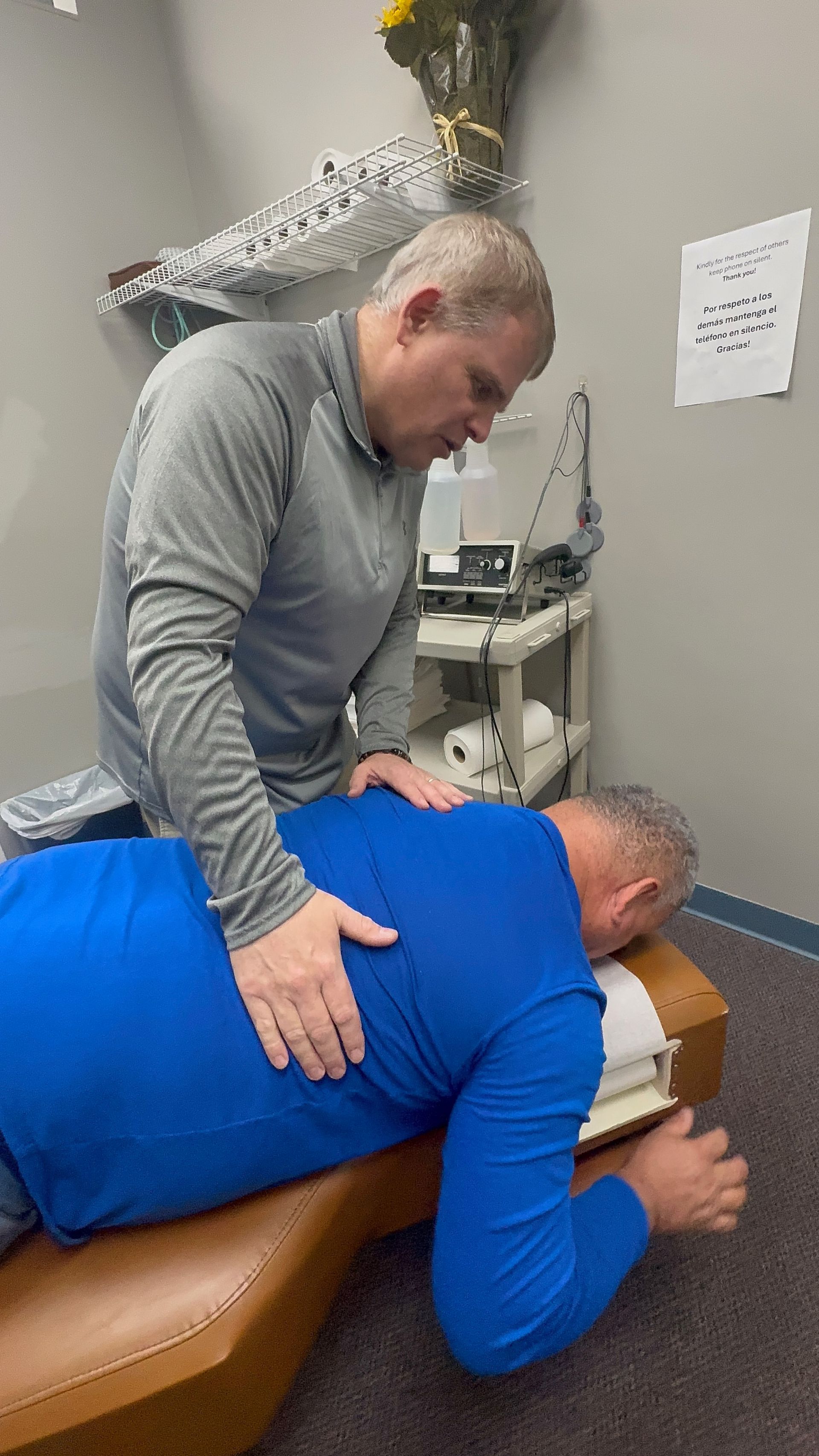 Chiropractor adjusting a patient's back on a table in an office.