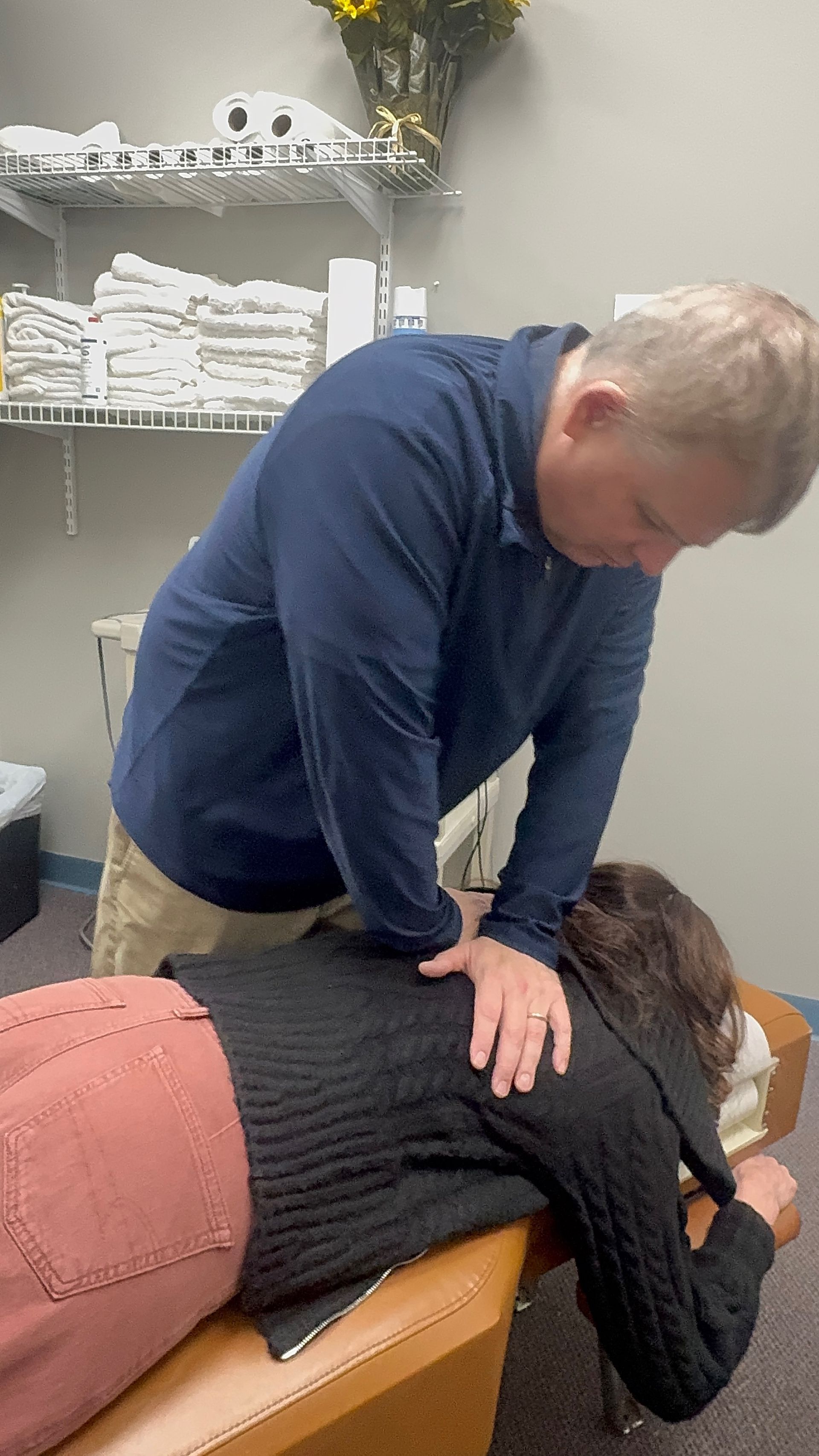 Chiropractor adjusting a patient's back in an office setting.