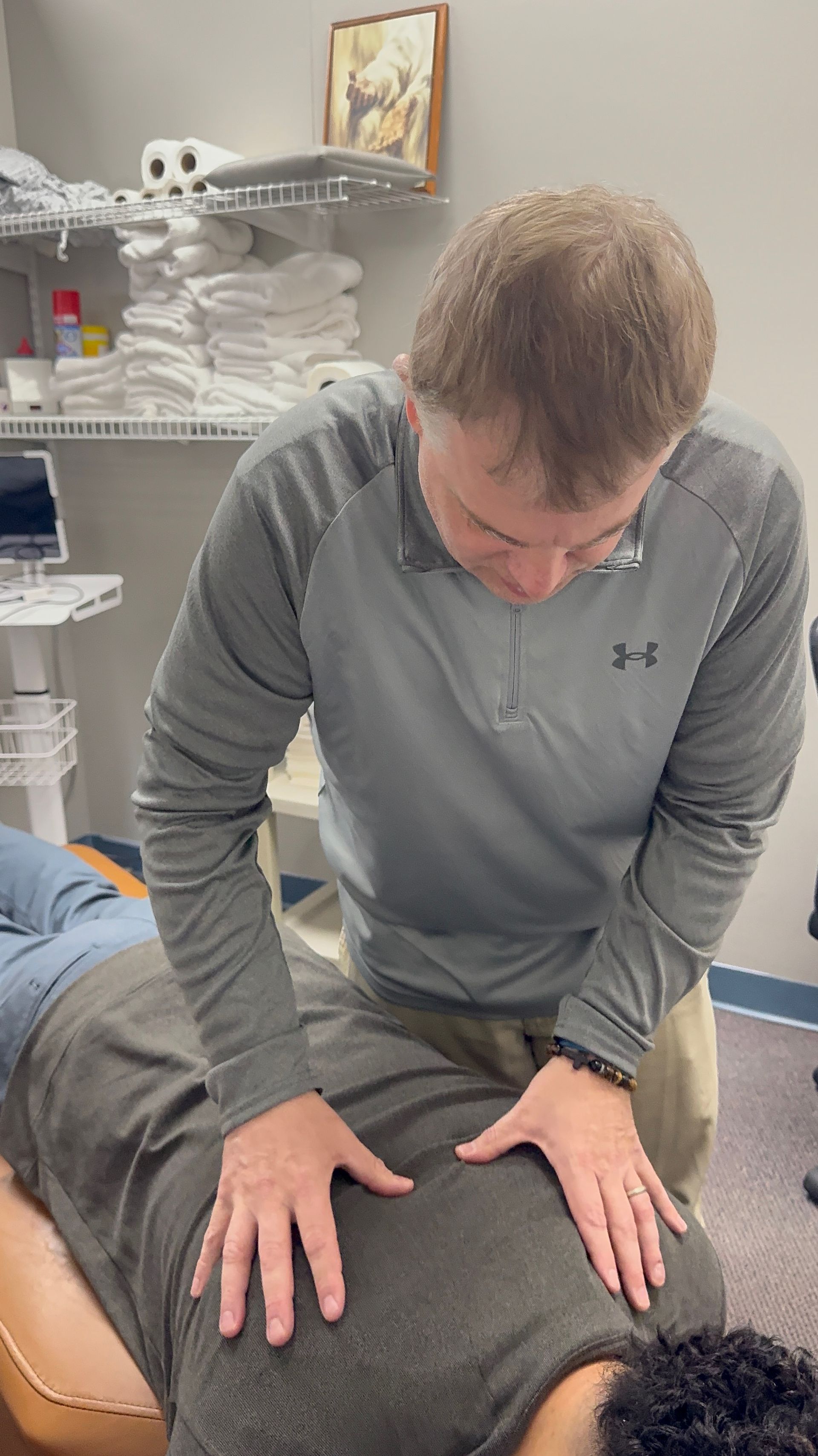A person receiving a back adjustment from another person in an office setting.
