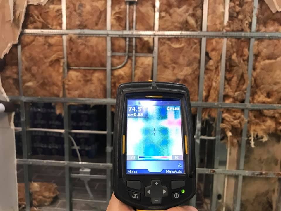 Thermal camera displaying temperature readings of a wall with insulation; the metal grid is visible.