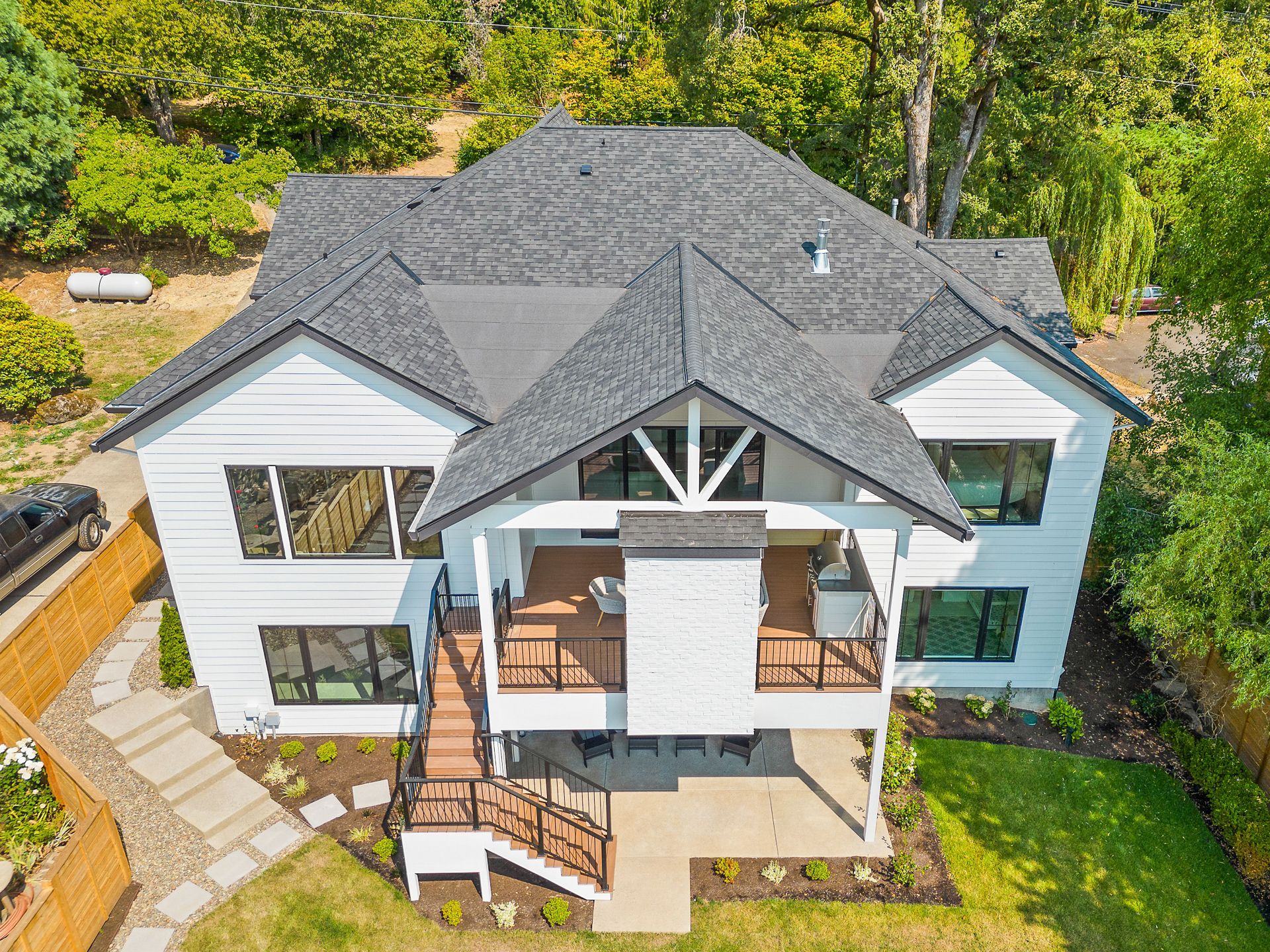 Drone photo of the back and side angle of a two story house showing the back and side yard view.