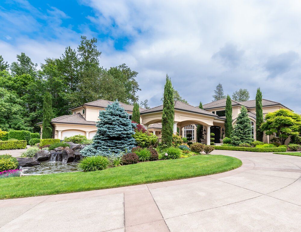 Picture of a long wrap around driveway in front of a big house.