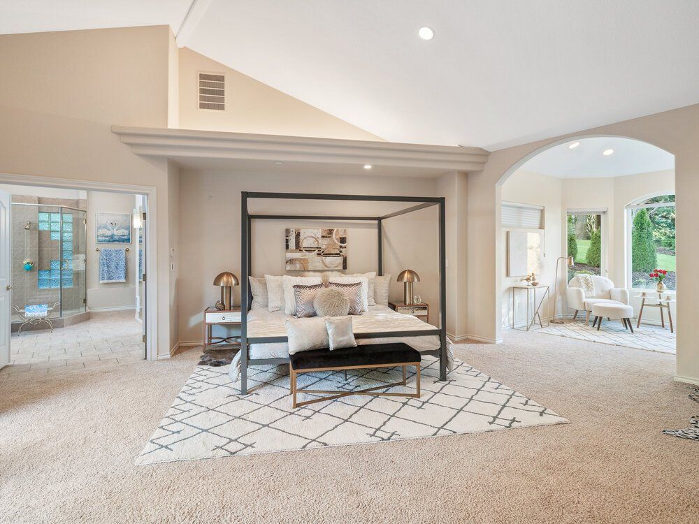 Photo of a bedroom with a bed in the middle and a nice rug underneath.