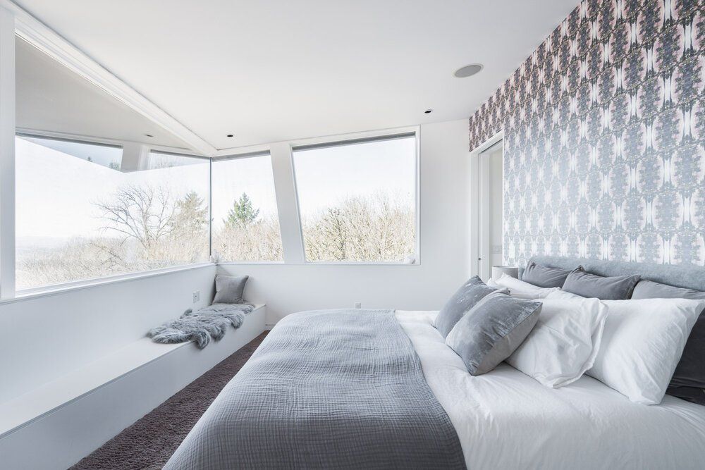 Photo of a bedroom with a large bed and windows overlooking a nice view.