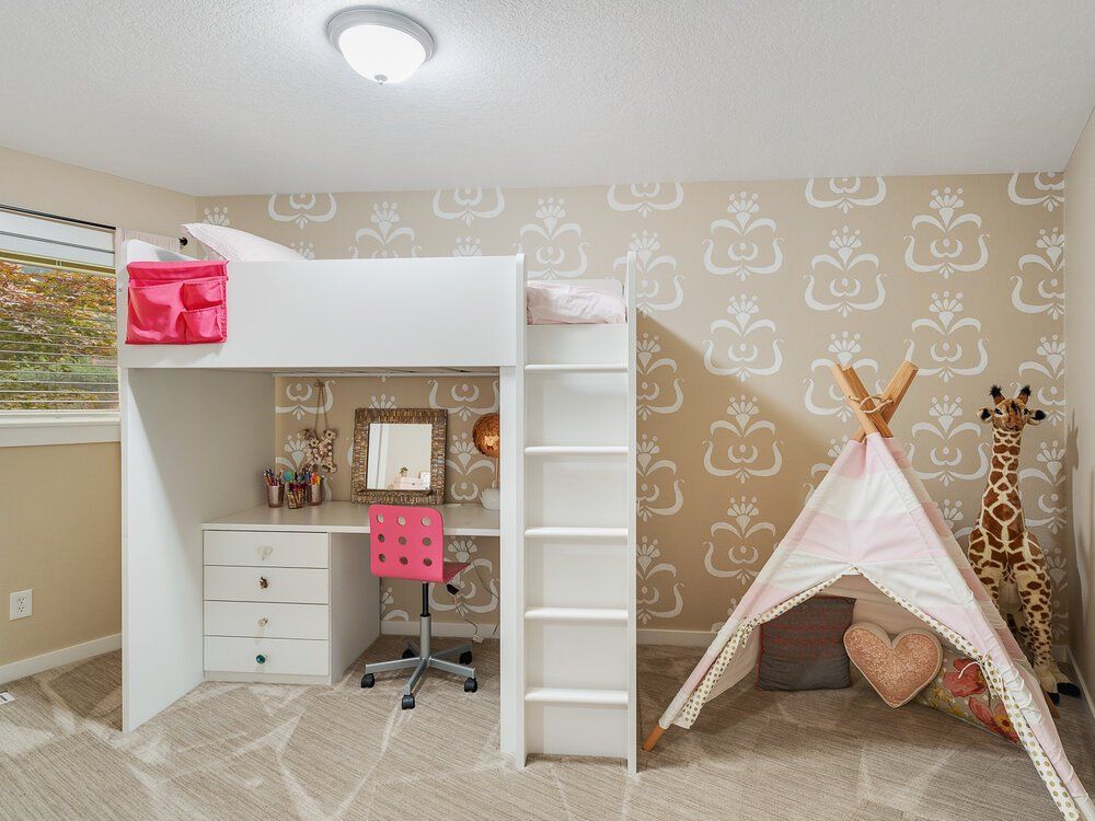 Photo of a kids room with a bunk bed on top and desk area on lower level and a tepee on the right.