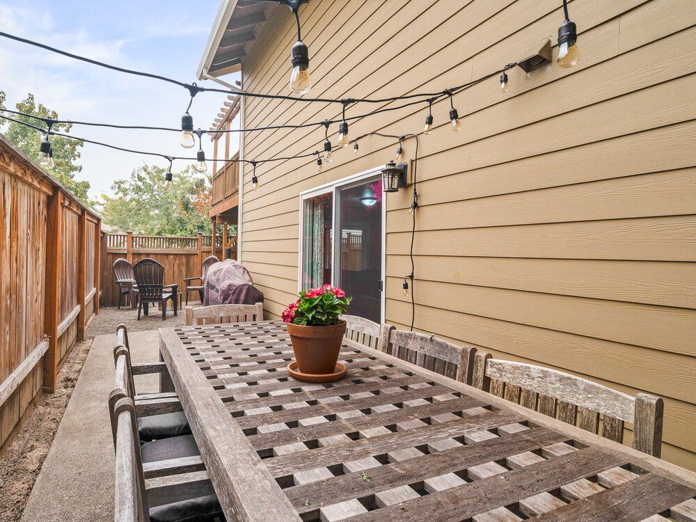 Photo of a side of a house with flowers and hanging lights.