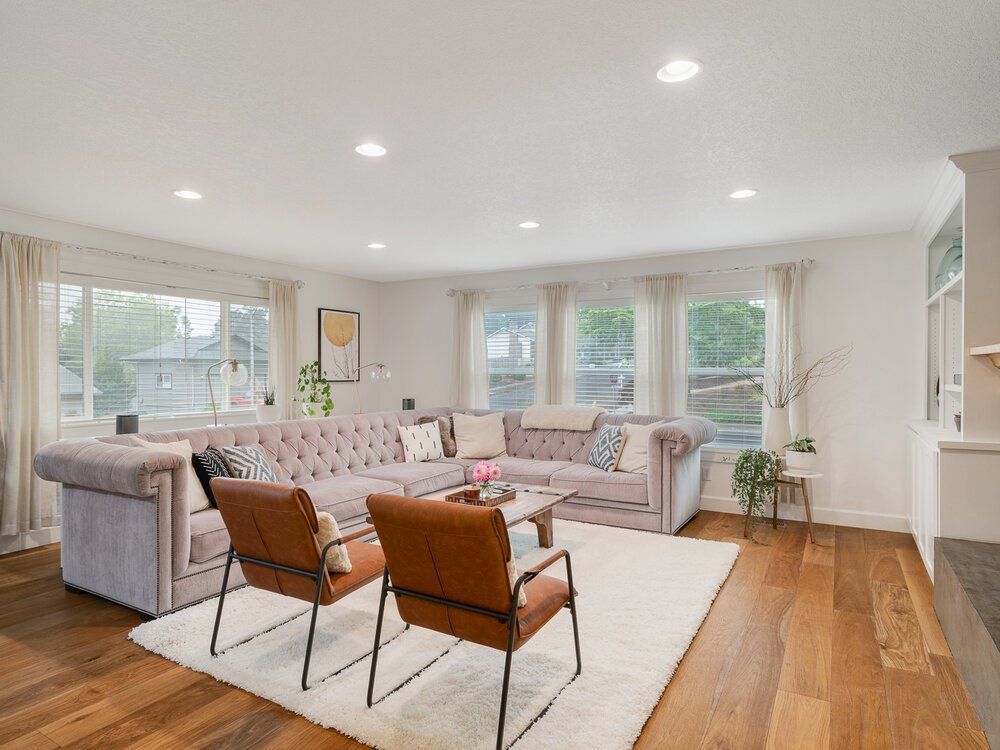 Photo of a living room with two chair at the front and windows towards the back of the photo.