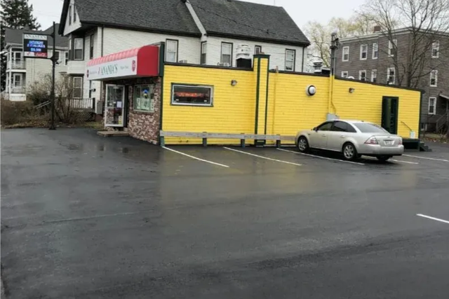 Yellow building with red awning, parked silver car, and wet parking lot.
