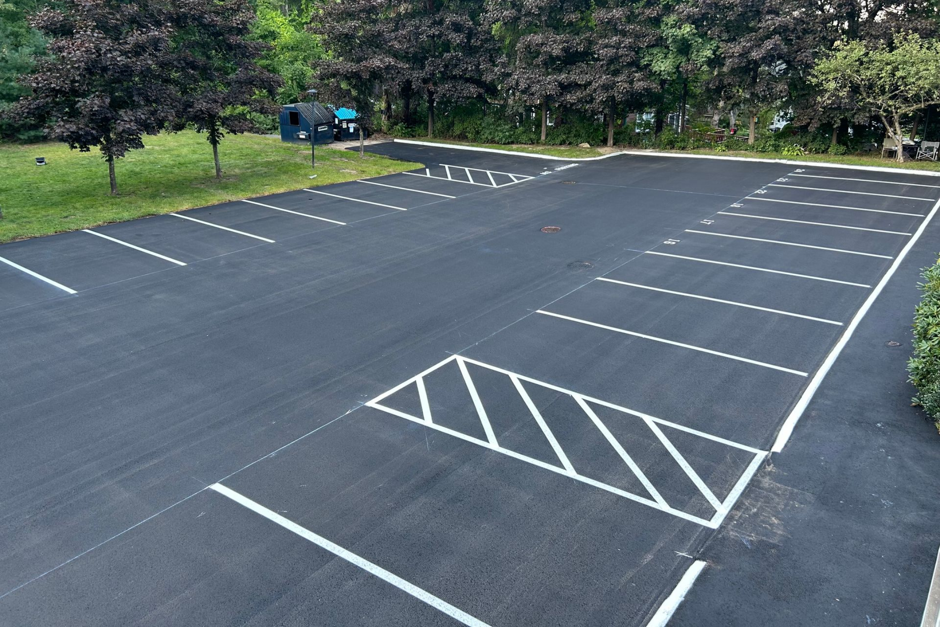 Newly paved asphalt parking lot with white painted parking space lines.