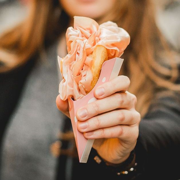 Una mano regge uno spuntino di street food appena preparato