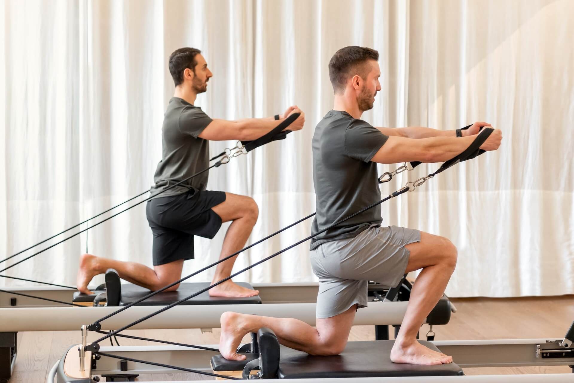 Two men doing kneeling resistance-band exercises in a studio