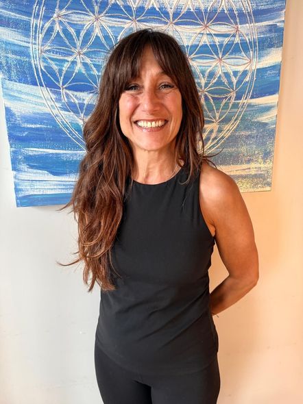 Smiling woman in black sleeveless top standing before a blue abstract painting
