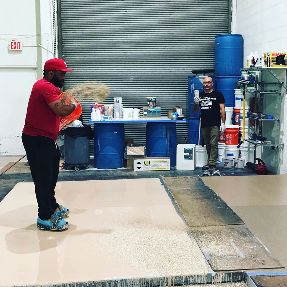 Person in red cap holding a ball in an indoor warehouse space with bins, shelves, and a metal door.