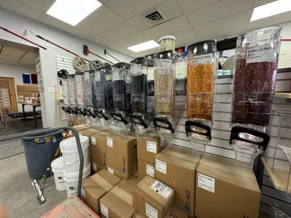 Row of bulk snack dispensers and cardboard boxes in a store stockroom or café storage area