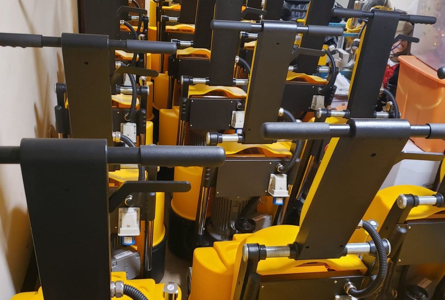 Rows of yellow and black exercise machines in a gym or fitness studio.