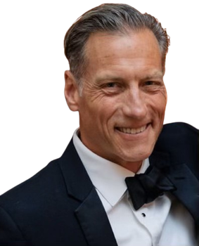Smiling man in a black tuxedo and bow tie against a white background