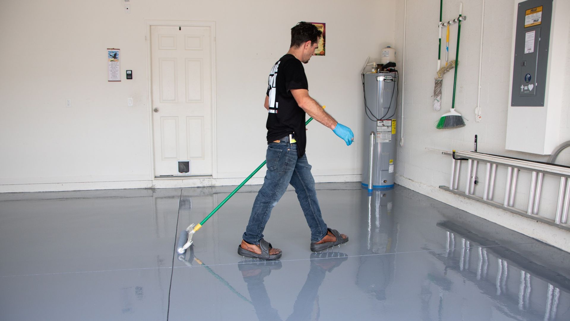 Worker mopping a glossy floor in a clean indoor room with equipment and wall fixtures.