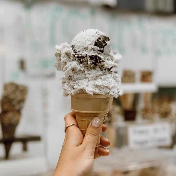 A person is holding a cone of ice cream in their hand.