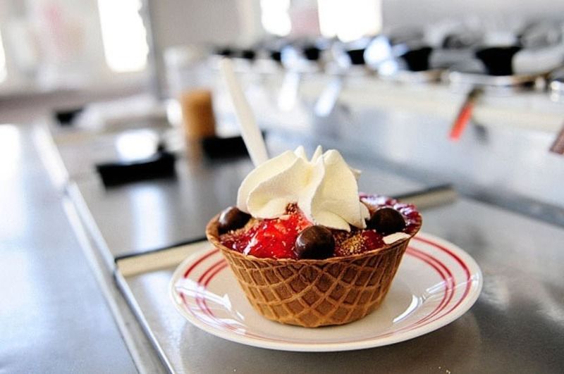 A waffle cup with whipped cream and berries on a plate