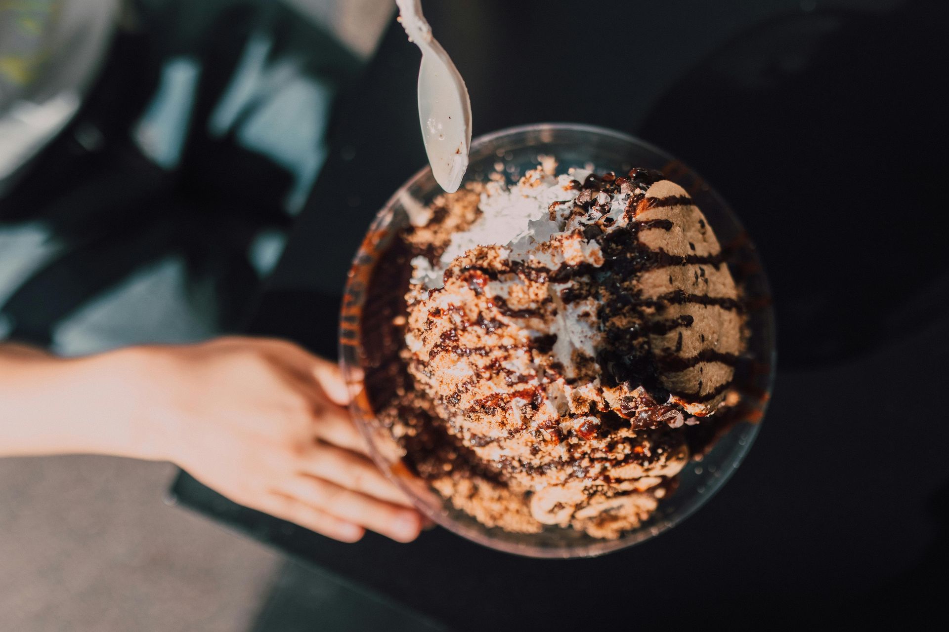 A person is holding a bowl of food with a spoon in it.