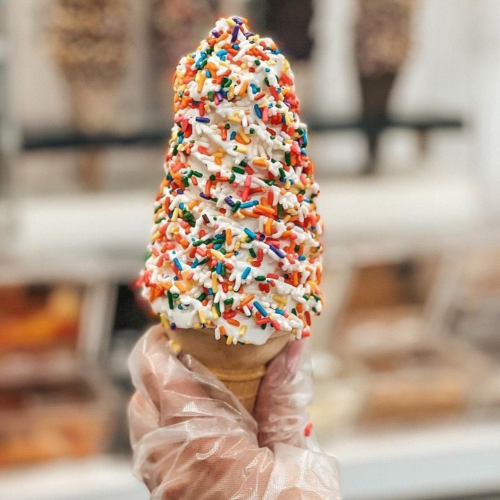 A person is holding an ice cream cone with sprinkles on top.