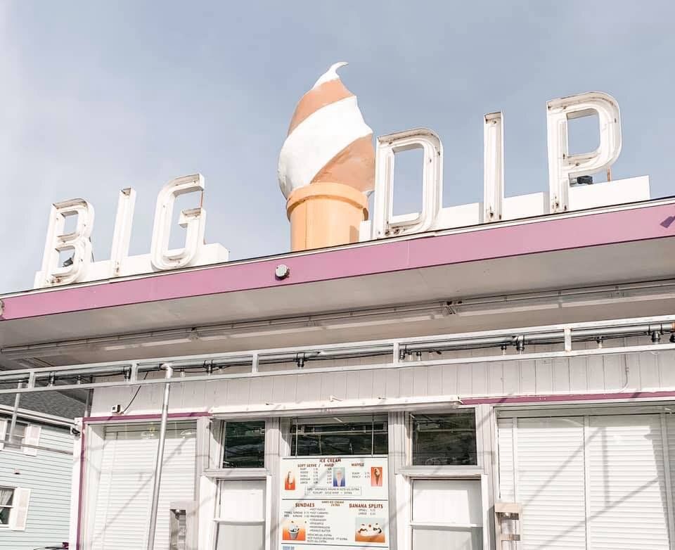 A large ice cream cone is on the roof of a diner called big dip